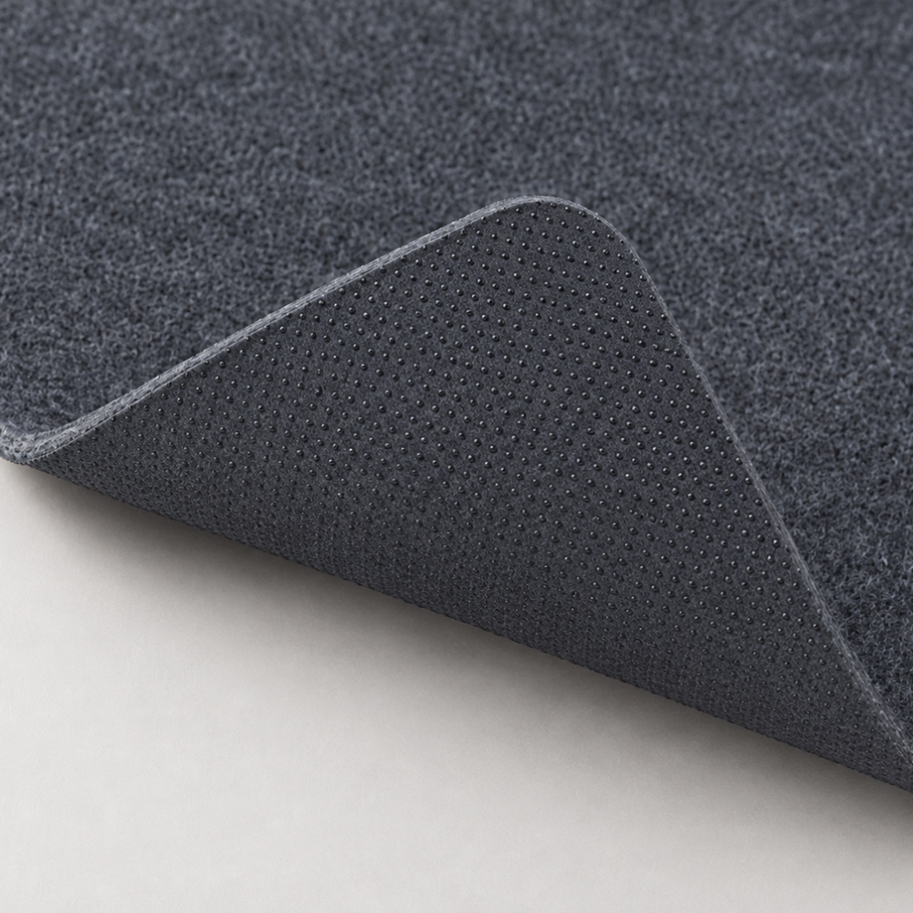Corner of The Felt Desk Mat lifted to show the felt surface and anti slip backing